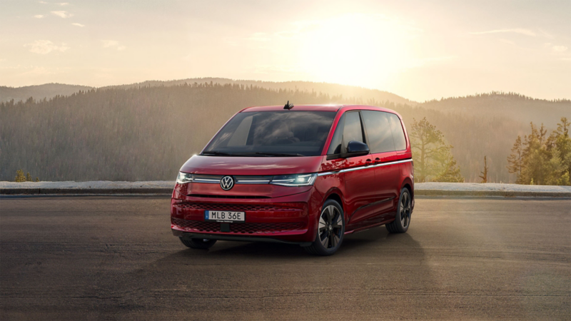En röd VW Multivan eHybrid står parkerad i solnedgången