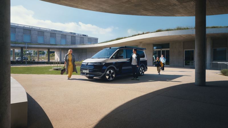 Familj står bredvid en parkerad VW California campingbil