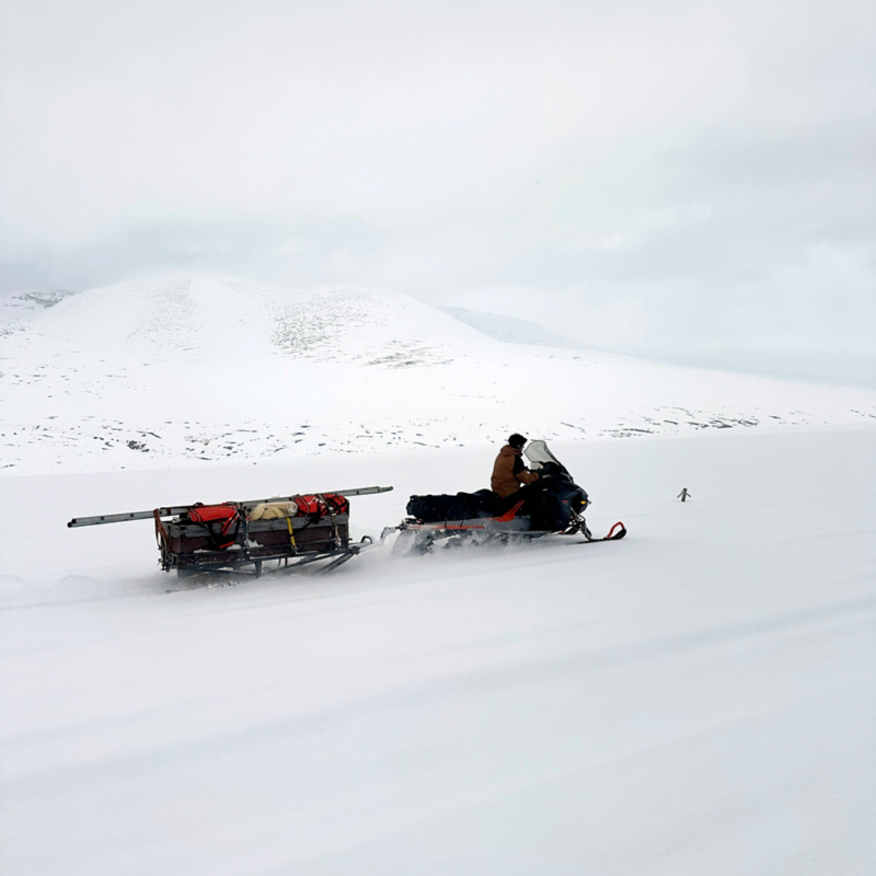 En person kör en skoter i fjällen