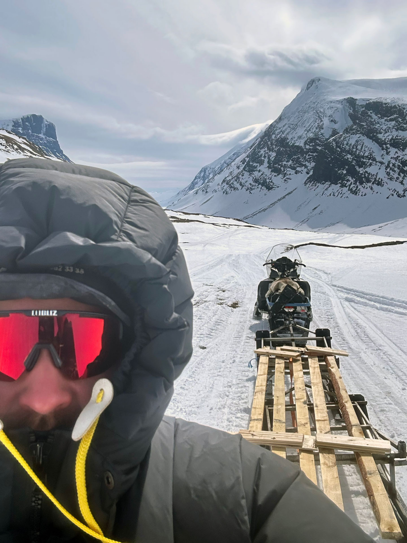 Jakob Berggren med vintermundering står bakom en skoter i vinterfjäll