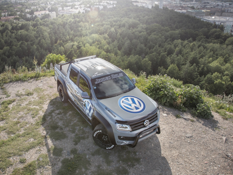 En grå VW Amarok pickup från generation 2 står parkerad på toppen av ett berg