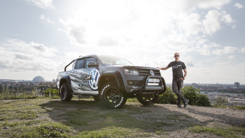 James Holm står med sin gråa VW Amarok generation 2 med Globen i bakgrunden