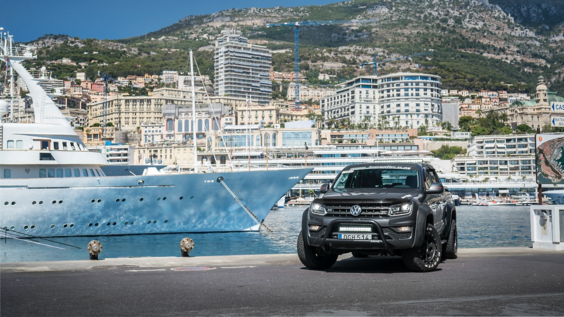 En grå VW Amarok generation 3 står parkerad i en hamn bredvid en yaht.