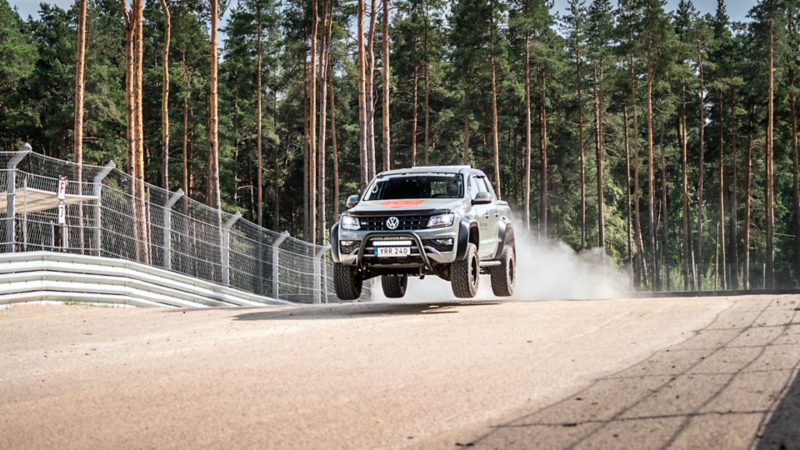Baksidan av en VW Amarok generation 3 kör på en racingbana och hoppar över ett krön