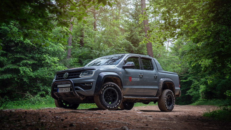 En grå VW Amarok generation 3 står parkerad i skogen