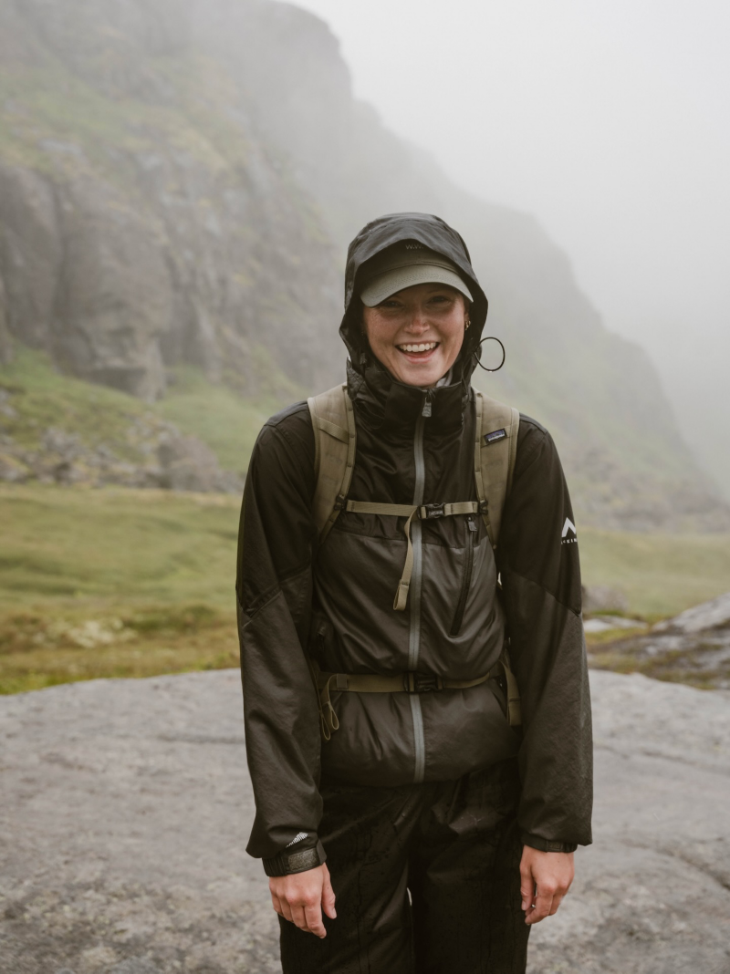 Astrid ler framför kameran iklädd regnkläder i ett regnigt Norge