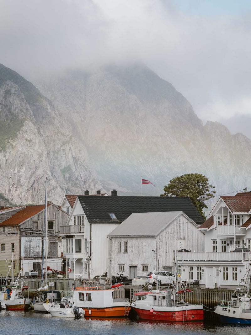 Hus och stugor vid hamnen vid Lofoten i Norge med dimmiga berg i bakgrunden