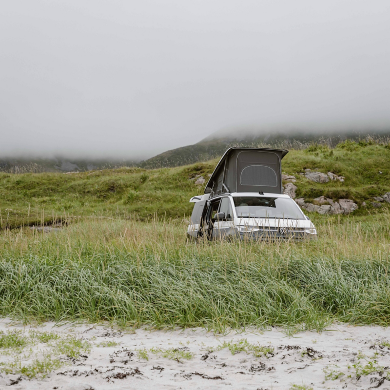 En VW California campingbil står parkerad vid kusten vid Lofoten i Norge
