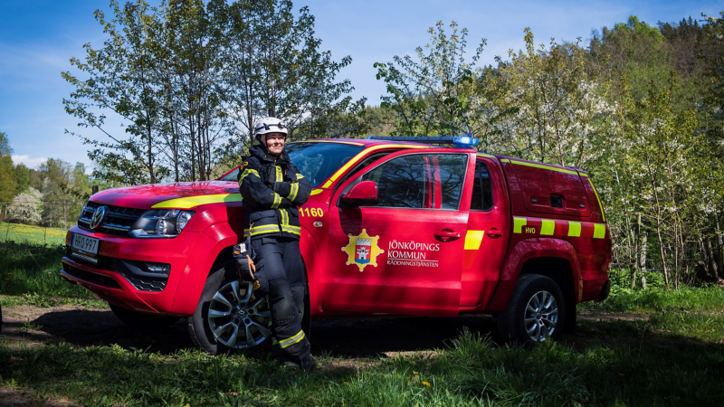 Brandmannen Elna står och lutar sig mot sin röda VW Amarok