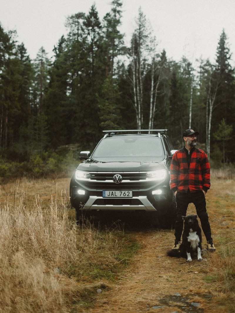 Oskar Snickrar står framför en VW Amarok tillsammans med sin hund