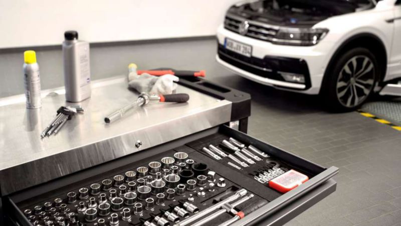 close up of tools and ratchet set with Volkswagen Golf in the background