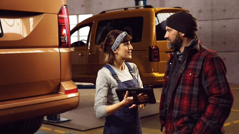 Kvinnlig biltekniker går igenom VW Approved med kund.