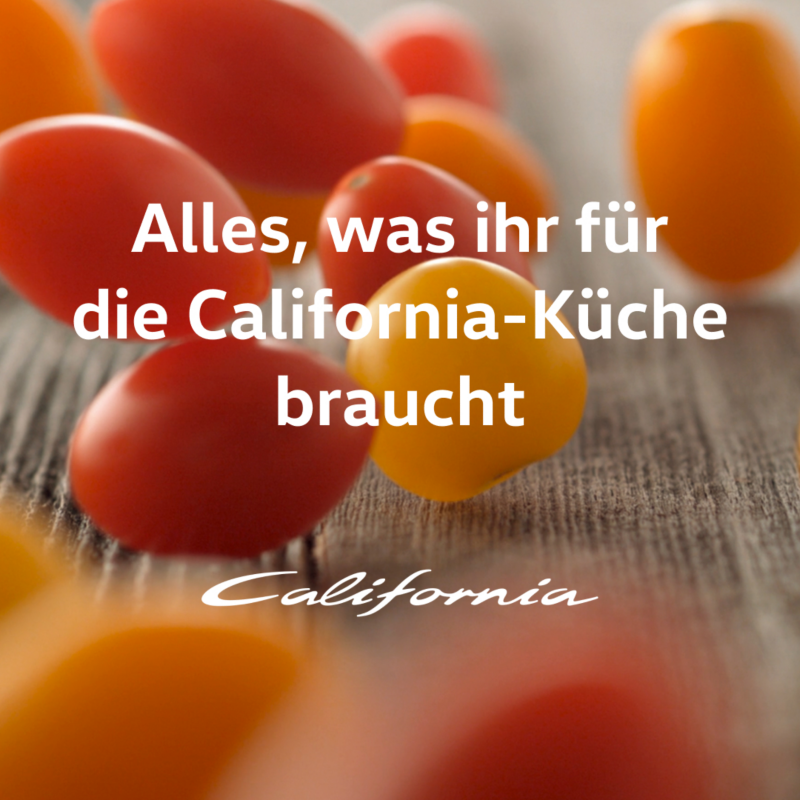 Rote und gelbe Cocktailtomaten fallen auf einen Tisch.