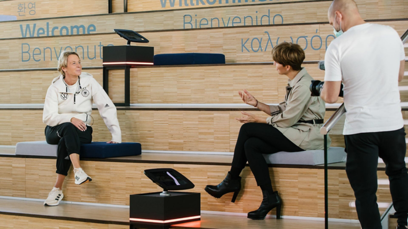 Martina Voss-Tecklenburg und Astrid Fontaine sitzen auf einer Zuschauertribühne