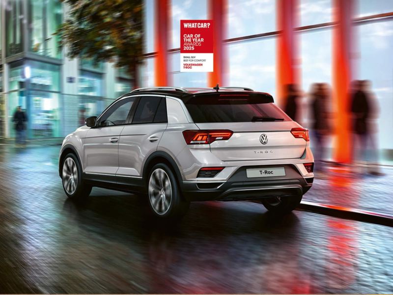 A silver T-Roc driving through a city at night