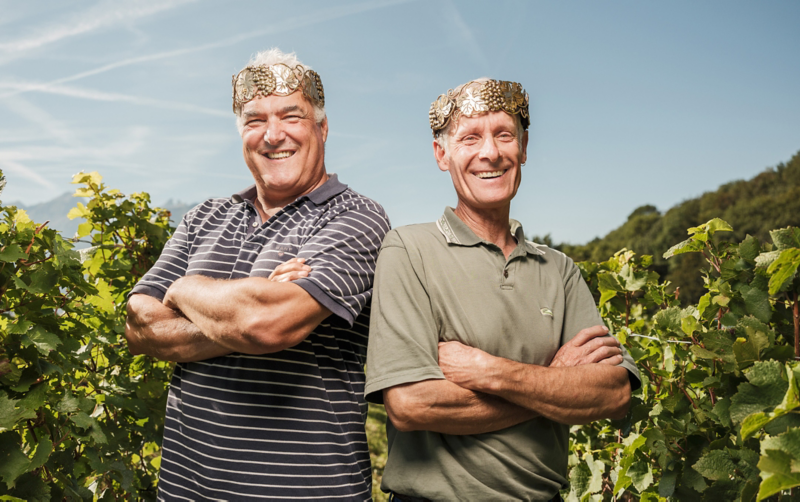 Die Winzerkönige stehen mit goldener Krone vor den Reben