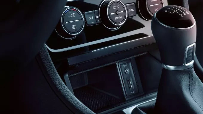  Gros plan de la console centrale d'une voiture, montrant un port USB, une prise auxiliaire et un levier de vitesses.