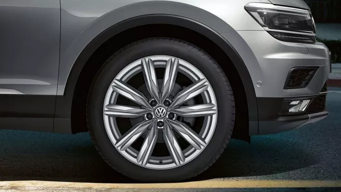 Gros plan sur la roue avant d'une voiture Volkswagen grise, montrant la jante et le pneu.
