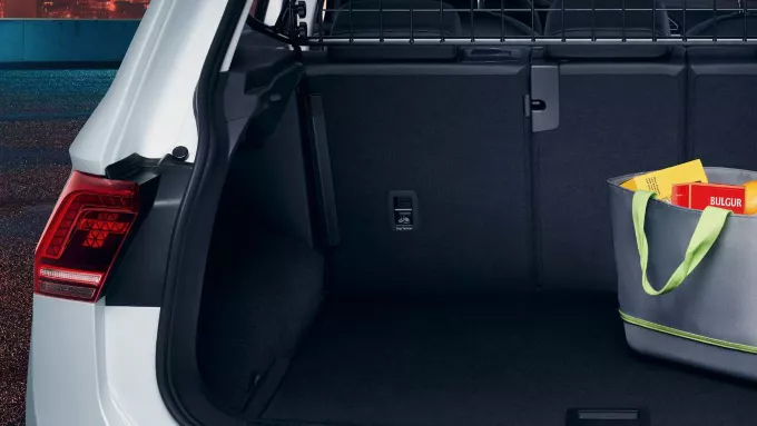 Le coffre ouvert d'une voiture, montrant un sac de courses gris avec des articles, dont un paquet de "BULGUR".
