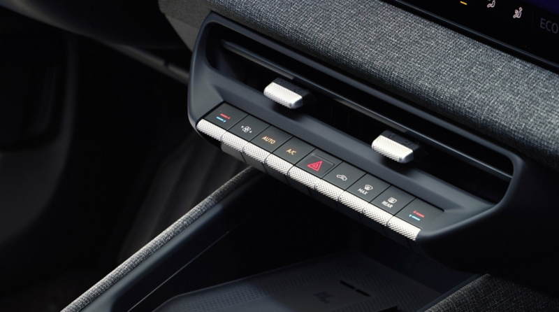 Volkswagen center console and climate controls with a wireless charging pad and fabric-trimmed dashboard.