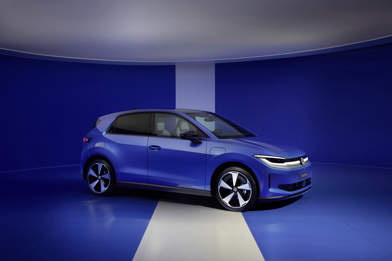 Front three-quarter profile view of a blue Volkswagen ID. Polo electric car parked across a thick white stripe in a blue studio showroom.