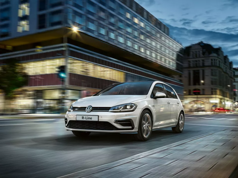 VW golf R-Line driving through a city at dusk