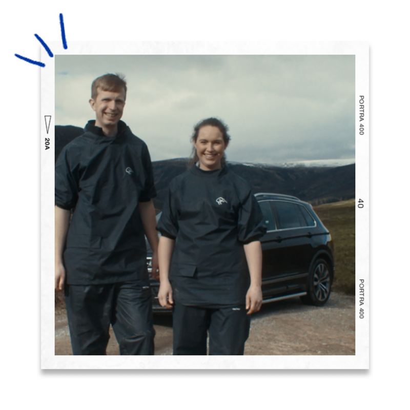 A couple standing next to their VW Touareg in a mountainous setting