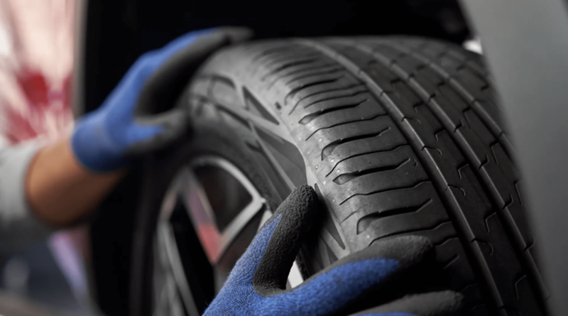 koło samochodu z oponą i ręce w rękawicach