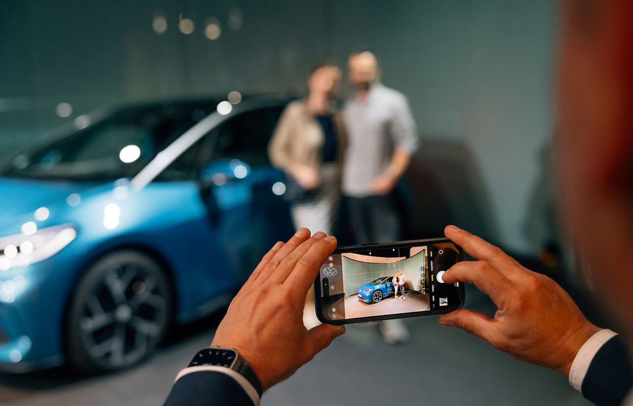 Eine Person Fotografiert Kunden bei der Auslieferung ihres blauen ID.3