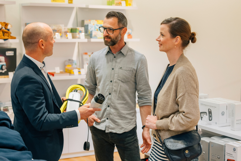 An employee advises a man and a woman in the shop of VW's transparent factory