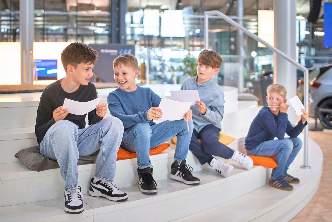 4 Kinder sitzen auf einer Treppe und lösen ein Quiz zur Kits Tour