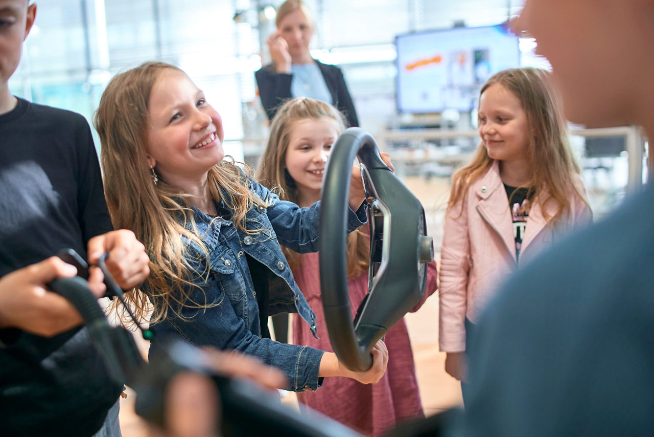 Ein Mädchen hält ein Lenkrad eines ID 3 bei einer Kids Tour in der Hand