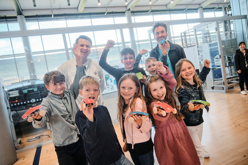 Children show their self-made electric model cars from the school lab
