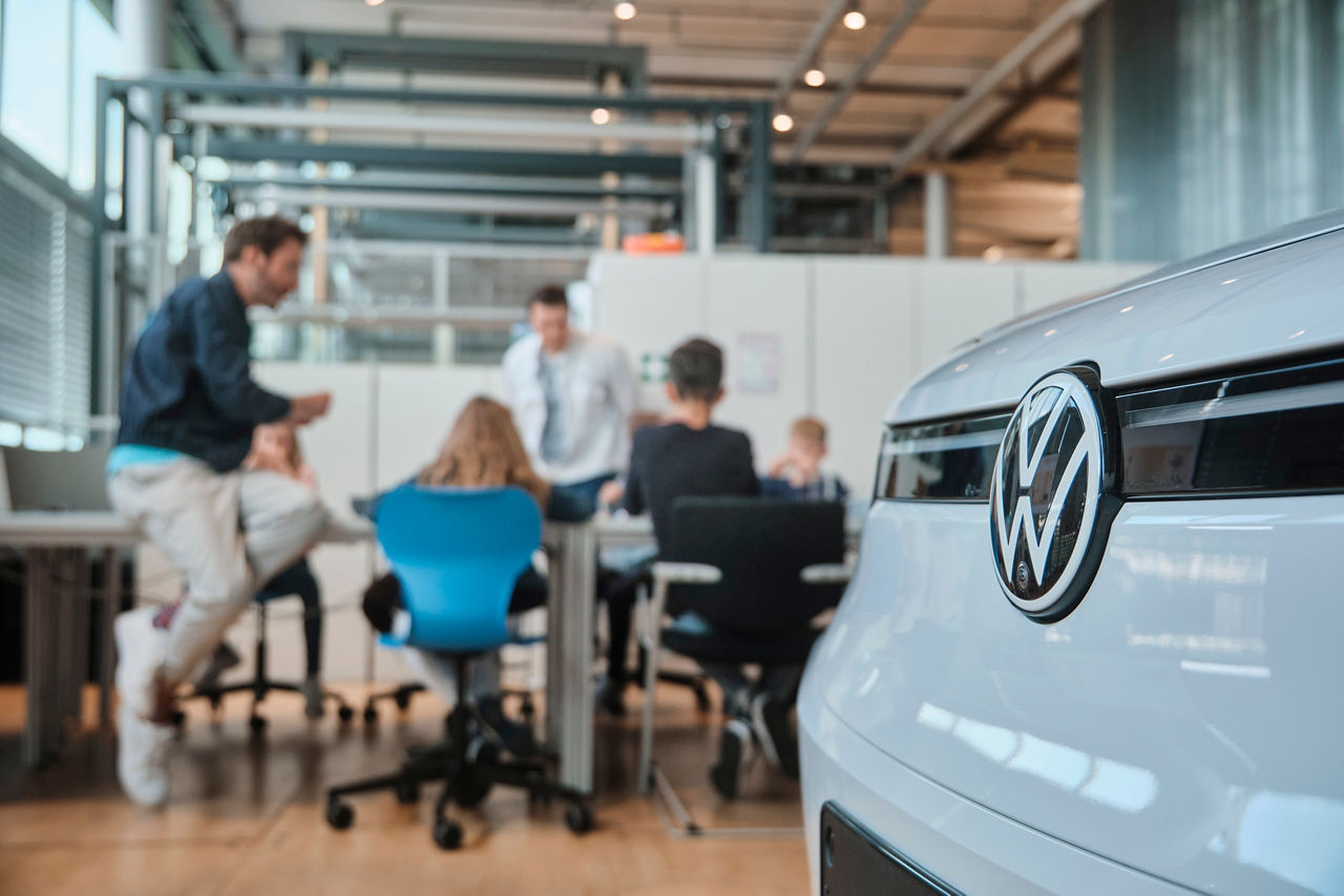Kinder und Mitarbeiter zusammen mit einem Fahrzeug im Schülerlabor der Gläsernen Manufaktur 