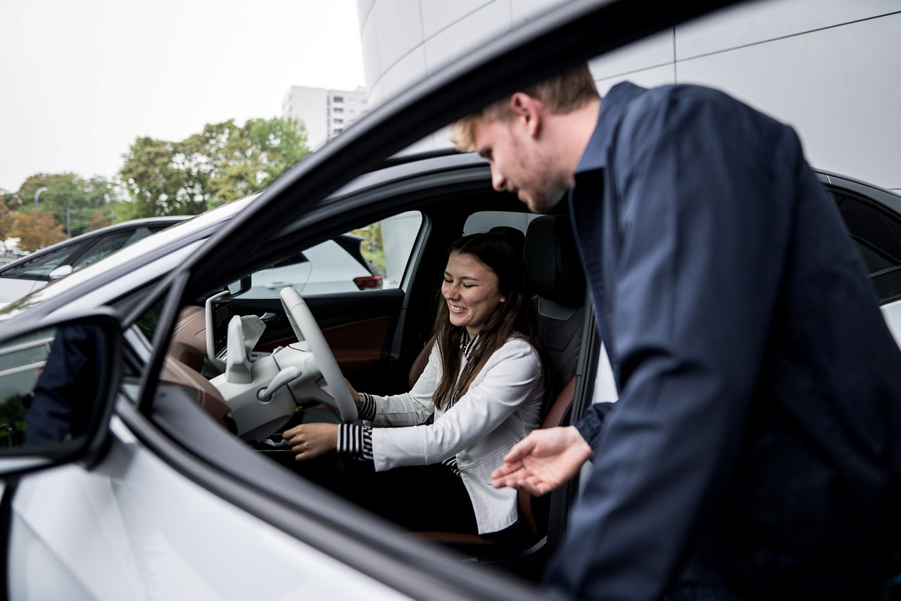 Eine Interessentin sitzt in einem Fahrzeug und wird von einem Mitarbeiter beraten