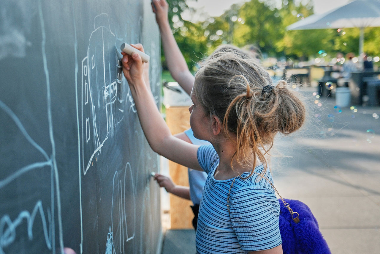 Kinder malen mit Kreide an eine Tafel