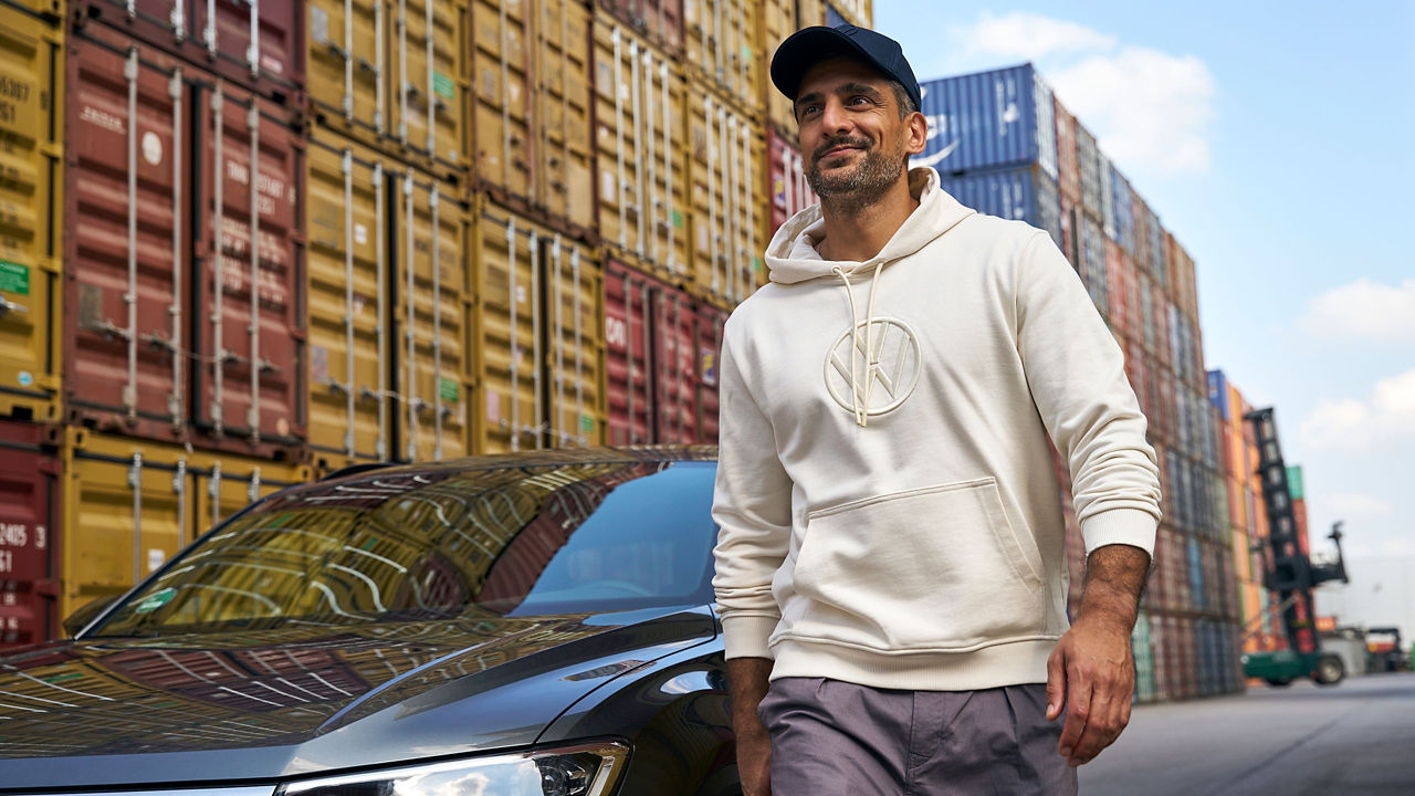 Mann läuft an VW Auto vorbei, im Hintergrund Container