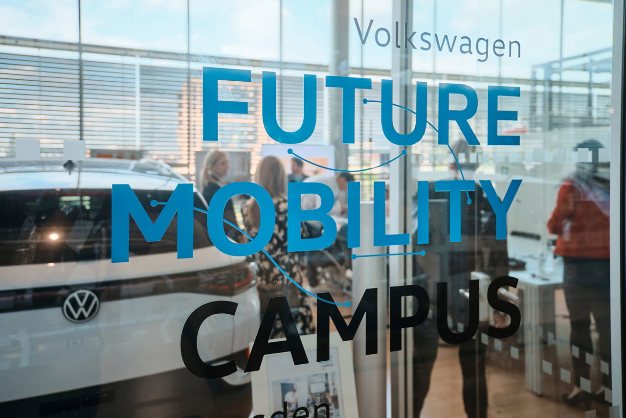 Der Future Mobility Campus mit Besuchern und einem Fahrzeug in der Gläsernen Manufaktur von VW