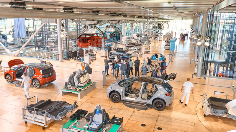Visitors and staff, as well as a number of car bodies, in the ‘Erlebniswelt’ area of the VW Transparent Factory in Dresden