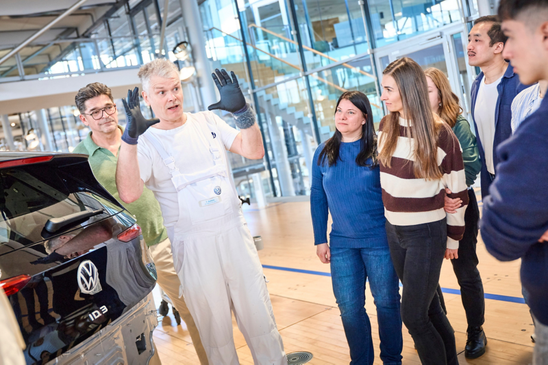 A worker explains the assembly of the driver's door of the VW ID.3