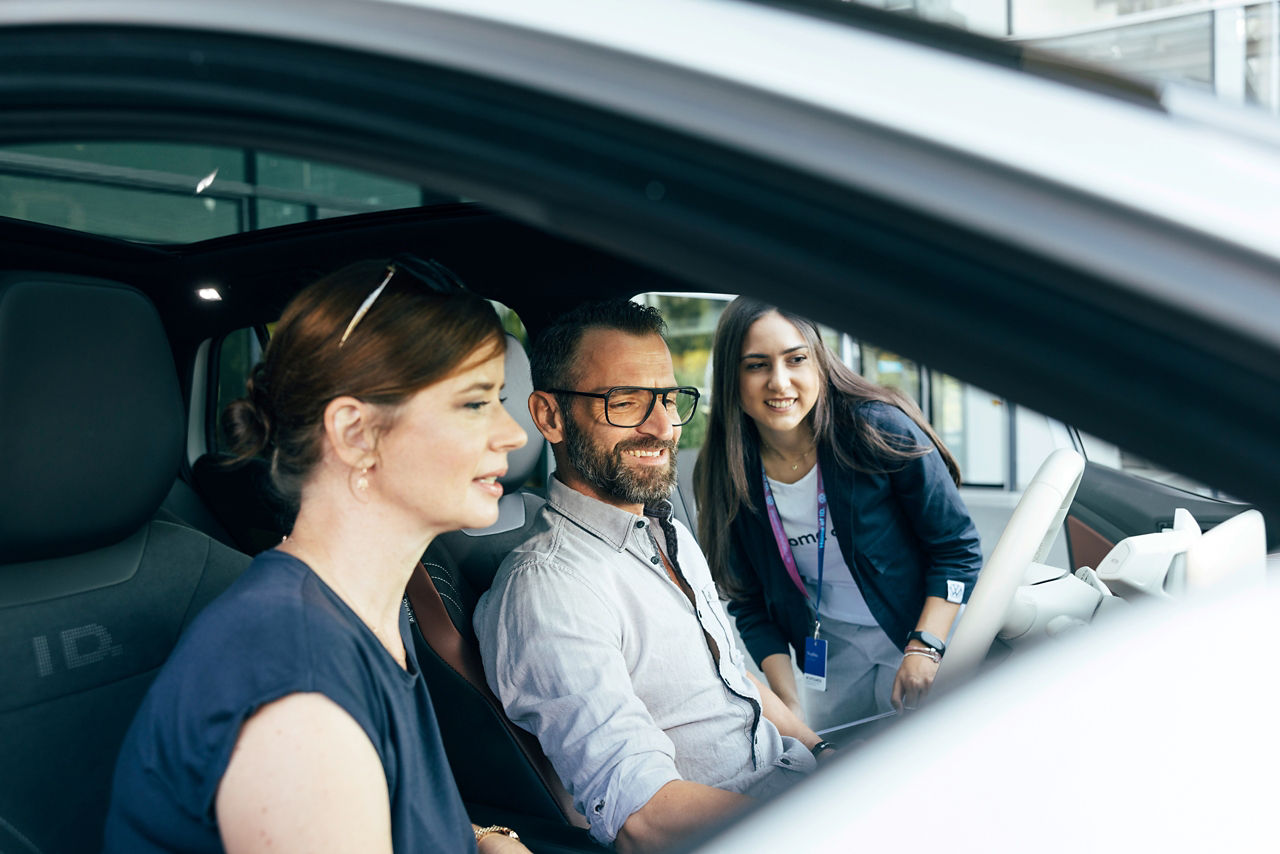 2 Personen in einem Fahrzeug werden von einem Guide zur Probefahrt  beraten